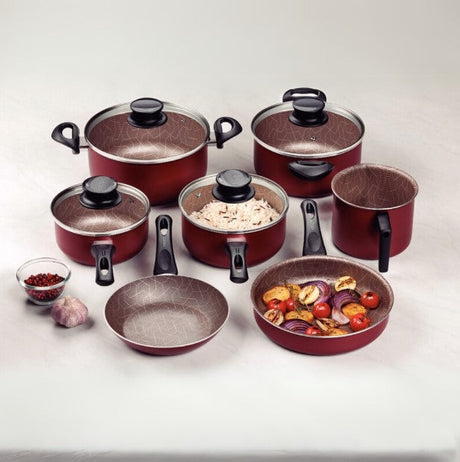 Set of red non-stick cookware, including pots, frying pans, and a saucepan, arranged with food ingredients on a neutral background.