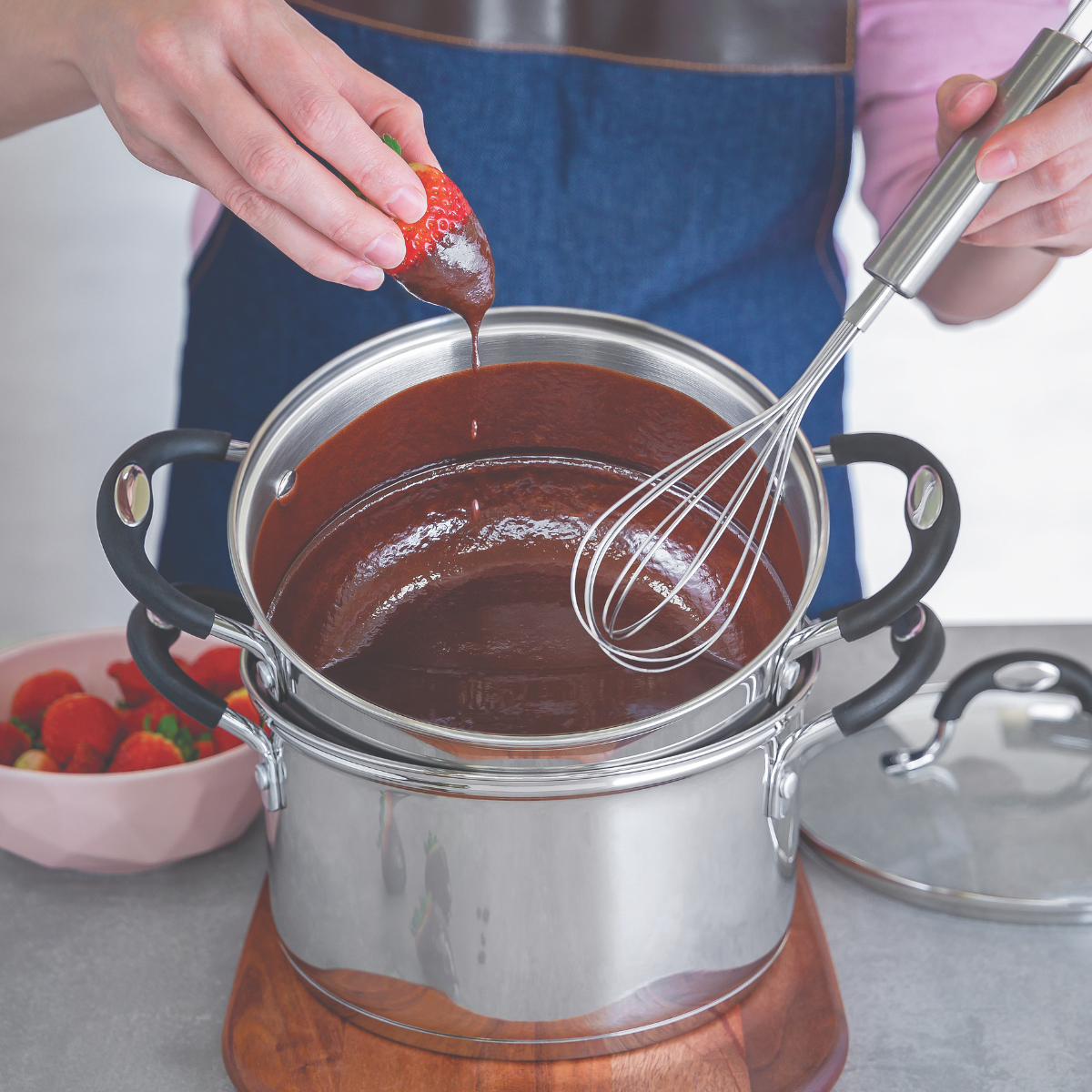 Silver stainless whisk with long wires held over a pot of chocolate