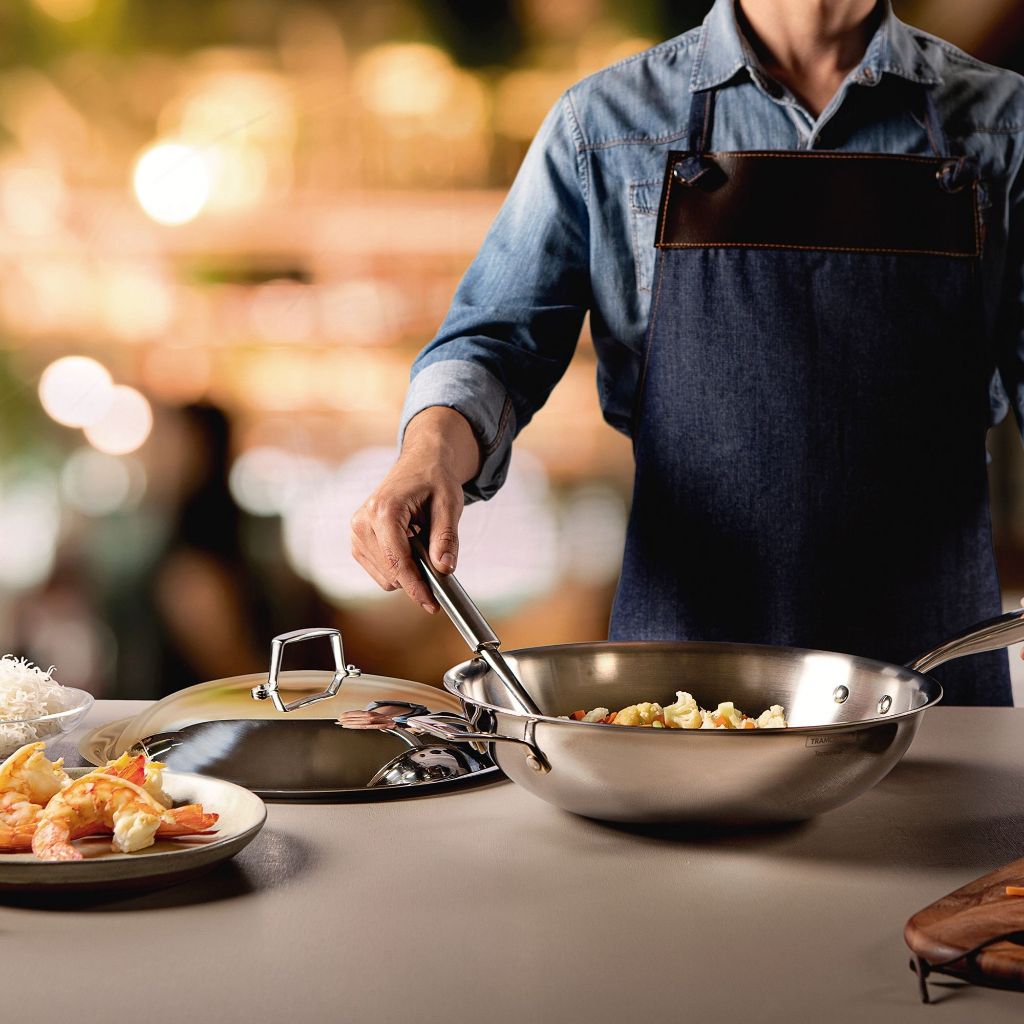 Stainless steel frying pan with two riveted handles and cooked food