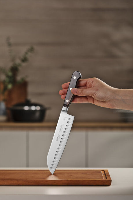 Hand holding a Tramontina Century santoku knife in a home kitchen